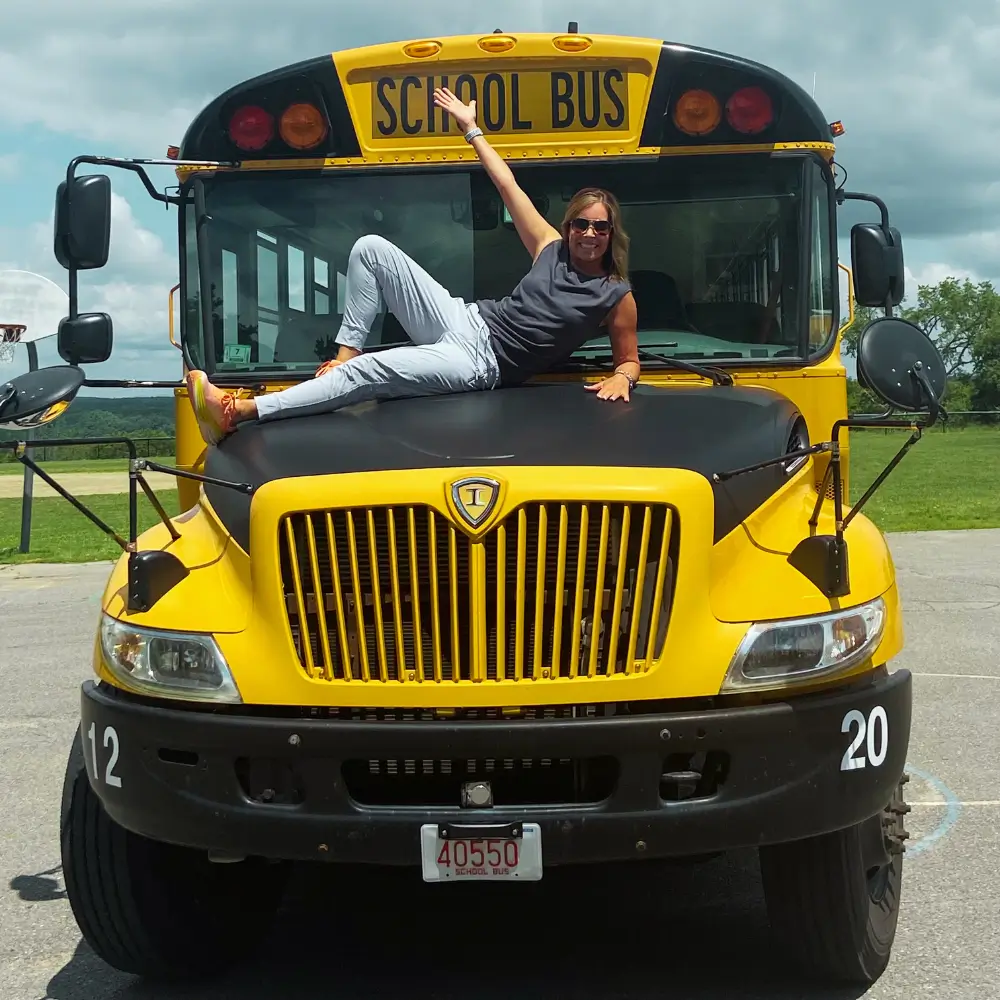a woman laying on the hood of a school bus