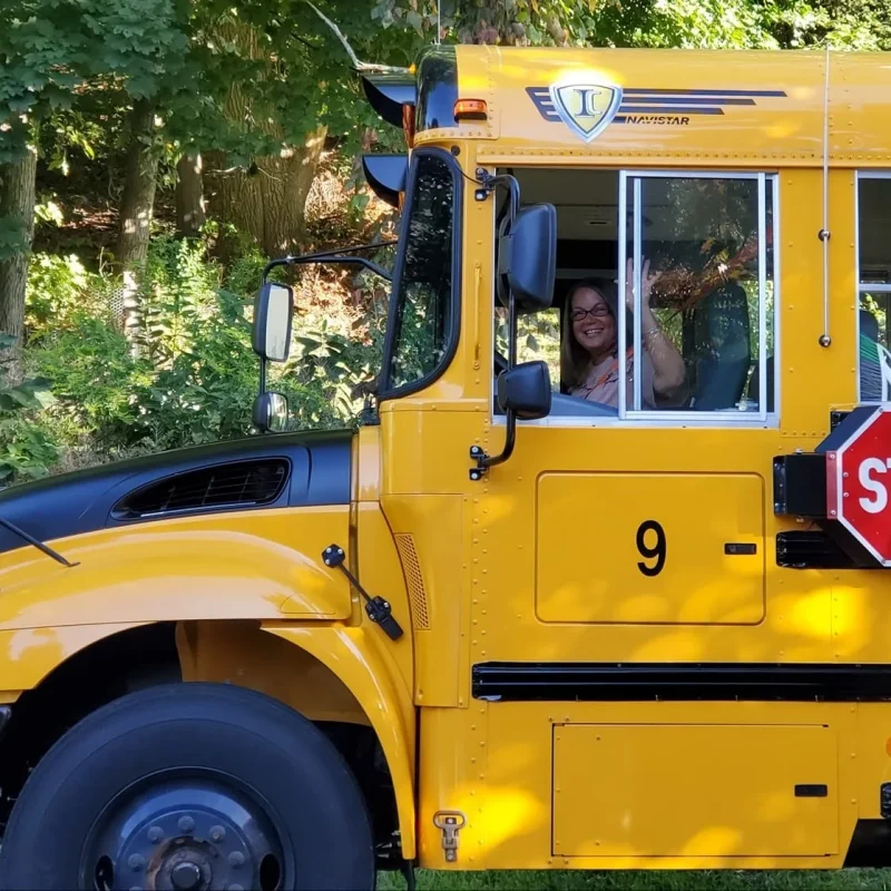 Legacy of Butler’s Bus Service a smiling woman in the window of a school bus